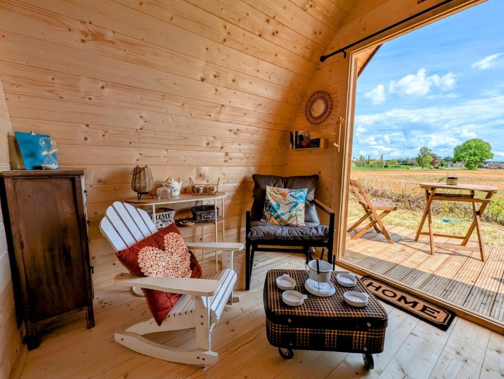 a cabin with a porch with a chair and a table at Cabane - Nature & Détente in Lavoncourt