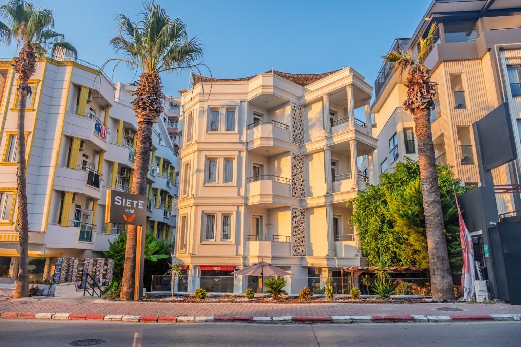 a building with palm trees in front of it at Siete Hotel in Antalya