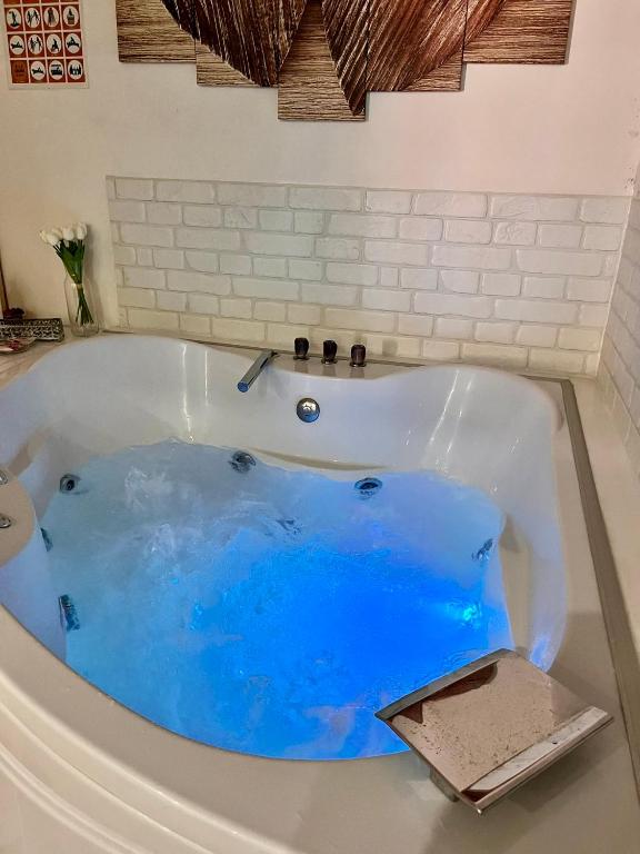 a bath tub with a blue water in it at SPA apartman in Kragujevac