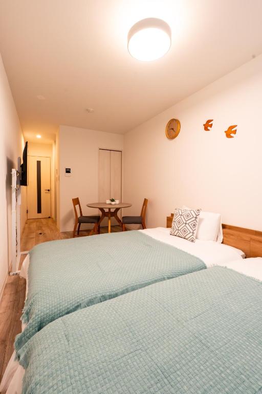a bedroom with two beds and a table with chairs at Nagomi Apartment Hotel in Hatsukaichi