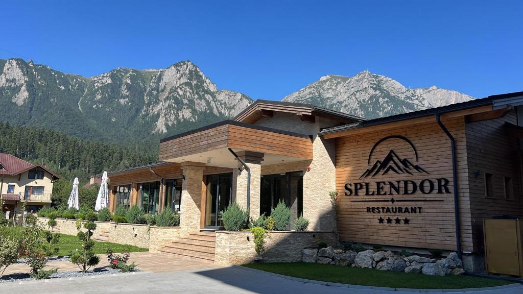 a building with a sign with mountains in the background at Hotel Restaurant Splendor in Buşteni