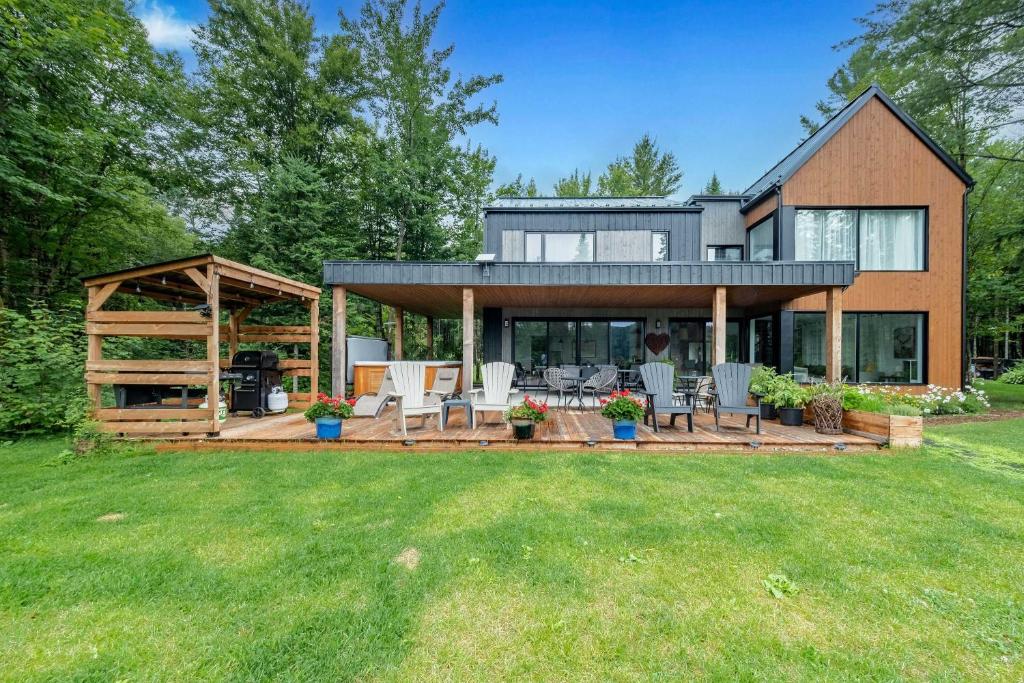 a house with a deck and chairs in the yard at Spa & River - Le Saint-Gabriel in Saint-Gabriel-De-Valcartier