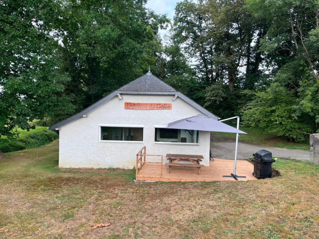 a small white building with a picnic table and an umbrella at L'Atelier de Gabs in Aramits