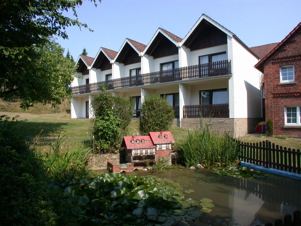 a row of houses with a pond in front of it at Hotel & Apartmenthaus Zum Pfingsttor in Friedrichswald