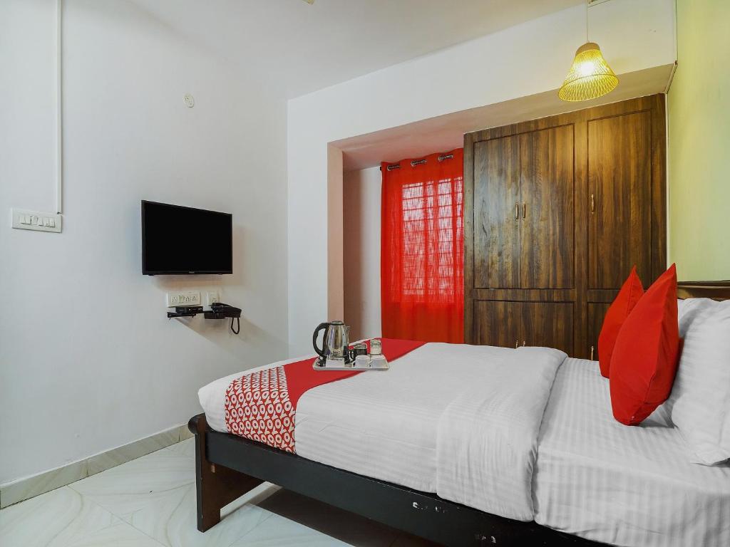 a bedroom with a bed with red pillows and a television at Hotel O RR in Kondapur