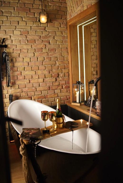a bath tub in a room with a brick wall at Magik Love Apartament in Piła