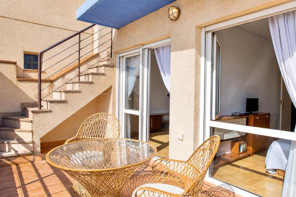 a glass table and chairs on a balcony with stairs at Aguamarina Ático Duplex Gran Terraza Cabo Roig in Orihuela