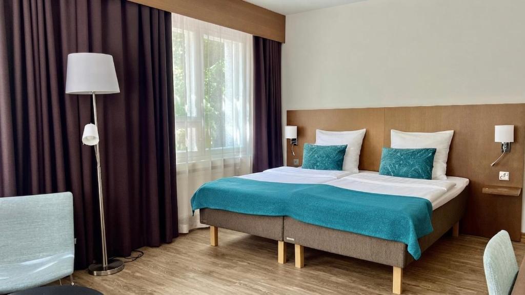 a bedroom with a large bed with a blue blanket at Hotel Raumanlinna in Rauma