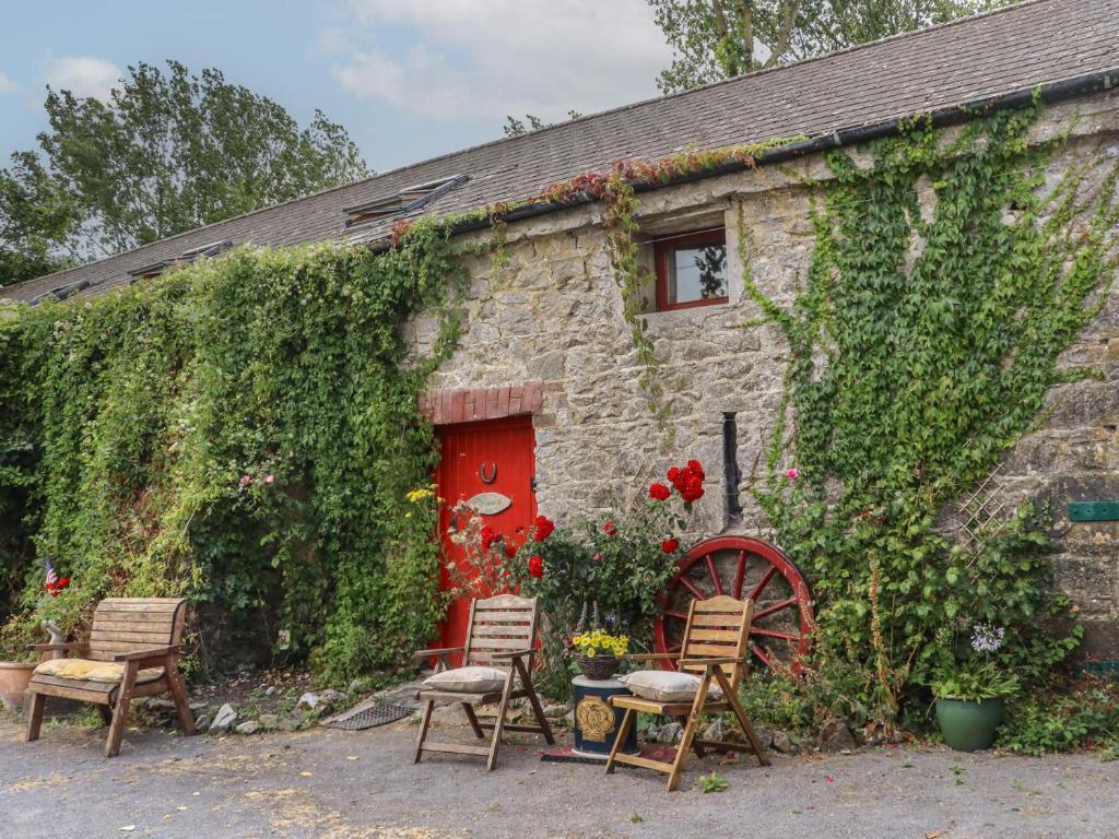 a stone house with chairs and a red door at Mrs Delaney's Loft in Ardfinnan