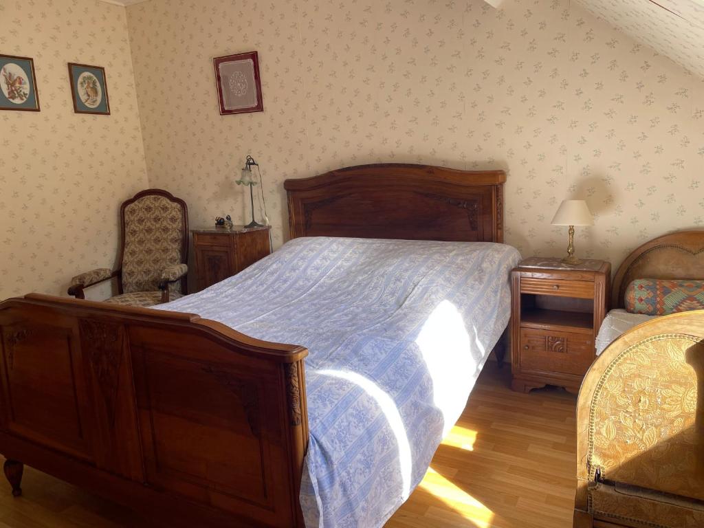 a bedroom with a large wooden bed and a chair at Chez Merlin le brocanteur in Charny