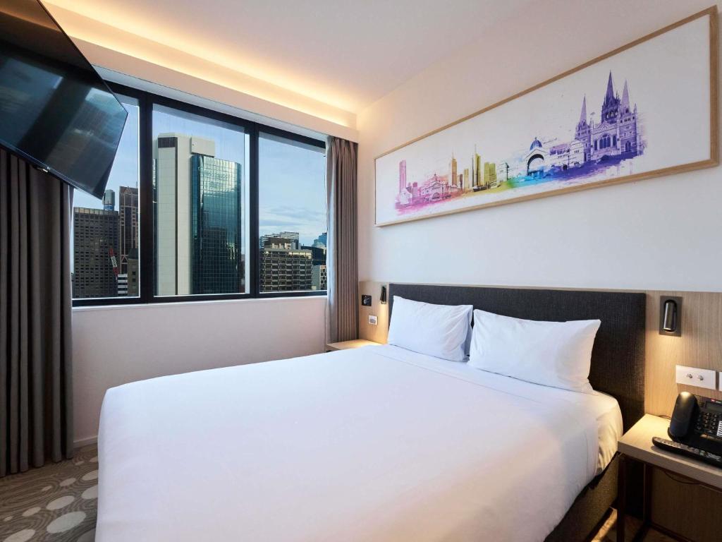 a hotel room with a bed and a large window at ibis Melbourne Central in Melbourne