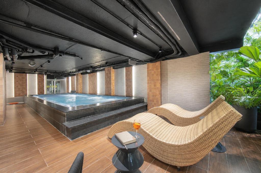 an indoor swimming pool with a wicker chair and a couch at MAY DE VILLE Prestige Hotel in Hanoi