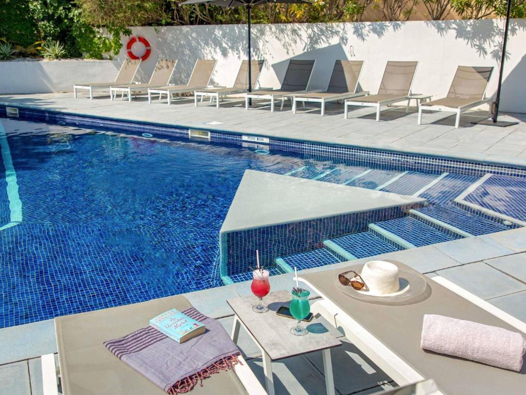 a swimming pool with chairs and a table next to it at Mercure Marseille Centre Bompard La Corniche in Marseille