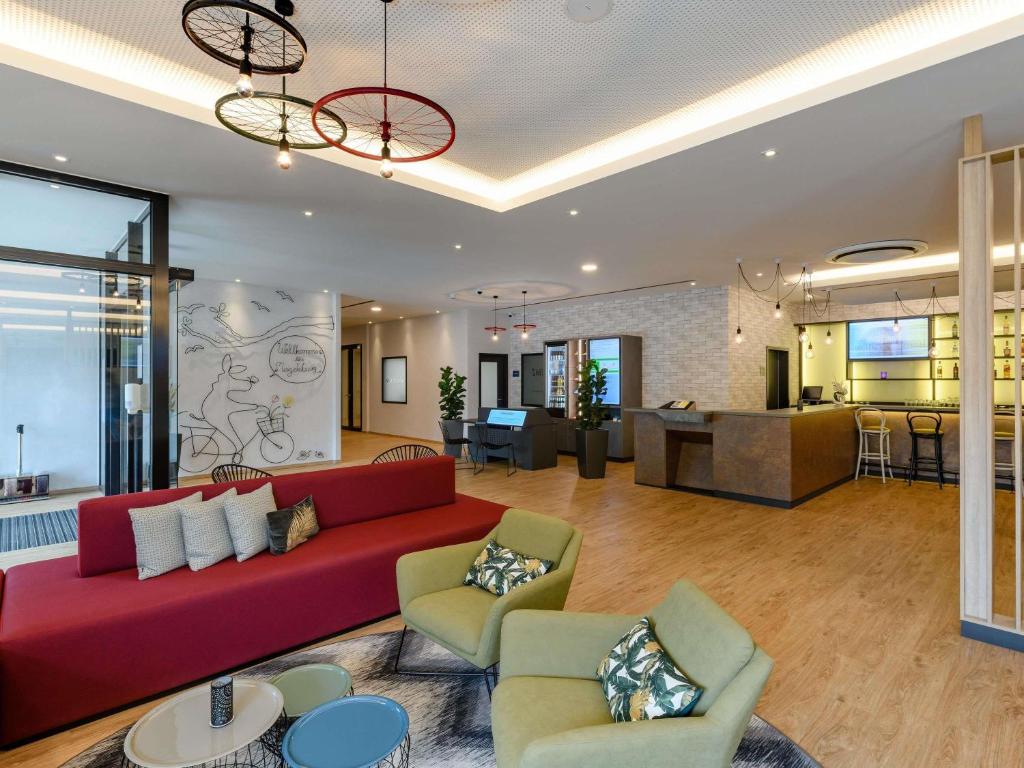 a living room with a red couch and chairs at ibis Styles Magdeburg in Magdeburg