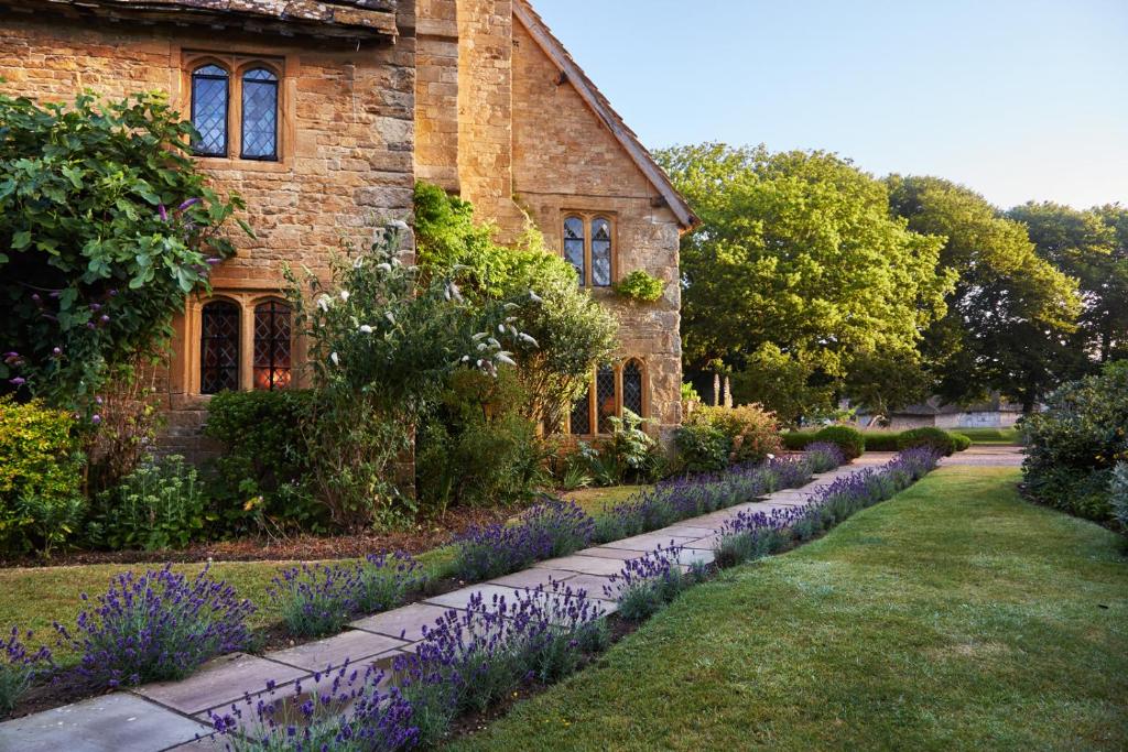 uma casa de pedra com flores roxas em frente em Bailiffscourt Hotel & Spa em Arundel