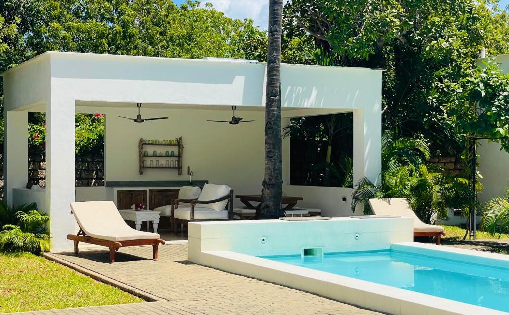 a swimming pool in a backyard with chairs and a table at Nyumba Nyekundu in Watamu