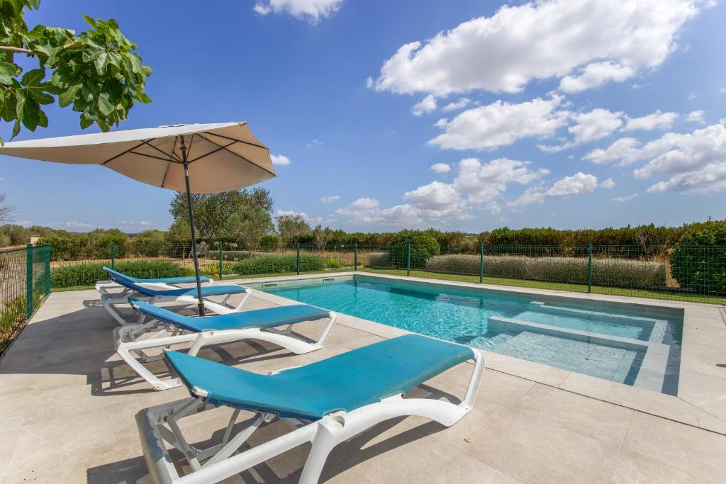 a pool with two lounge chairs and an umbrella at Sa Vinya d'Es Trenc in Campos