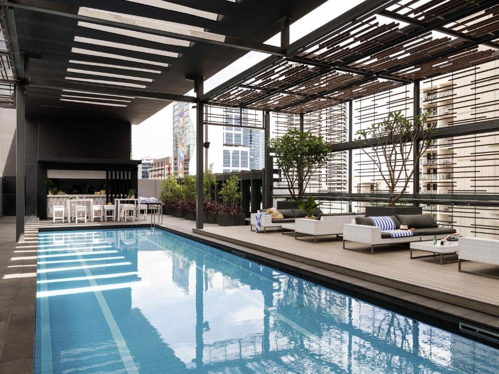 a large swimming pool in a building with chairs and tables at Novotel Perth Murray Street in Perth