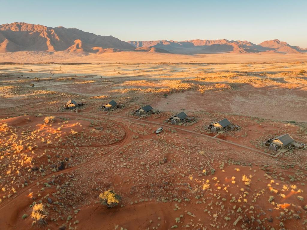 an aerial view of a desert with huts and mountains at Wolwedans Dune Camp in NamibRand