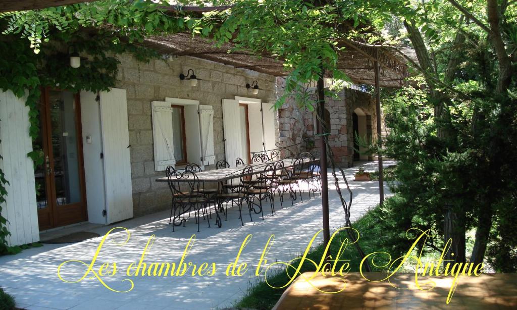 um pátio com cadeiras e uma mesa em frente a um edifício em Les chambres de l'Hôte Antique em Porto-Vecchio