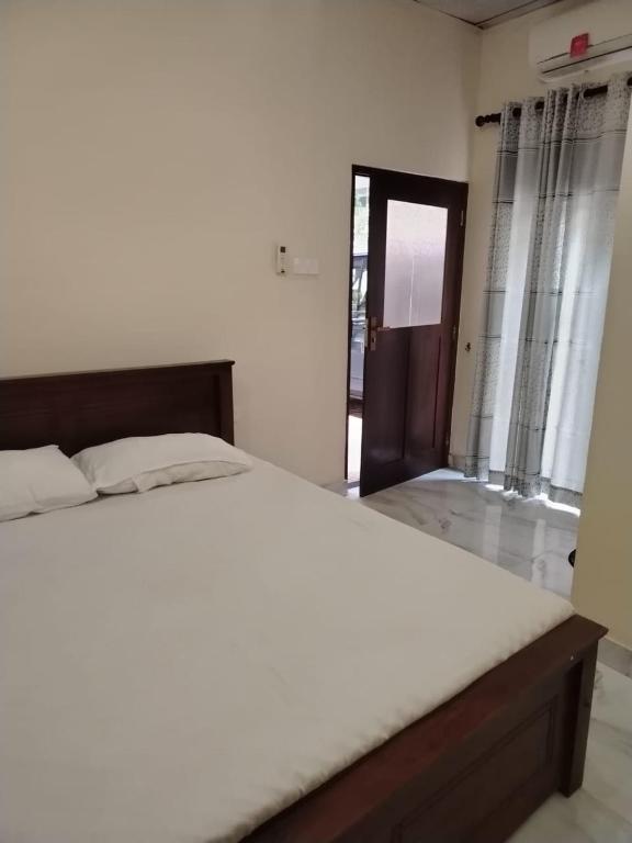 a bedroom with a bed and a door to a room at Sathkara Guest House in Anuradhapura
