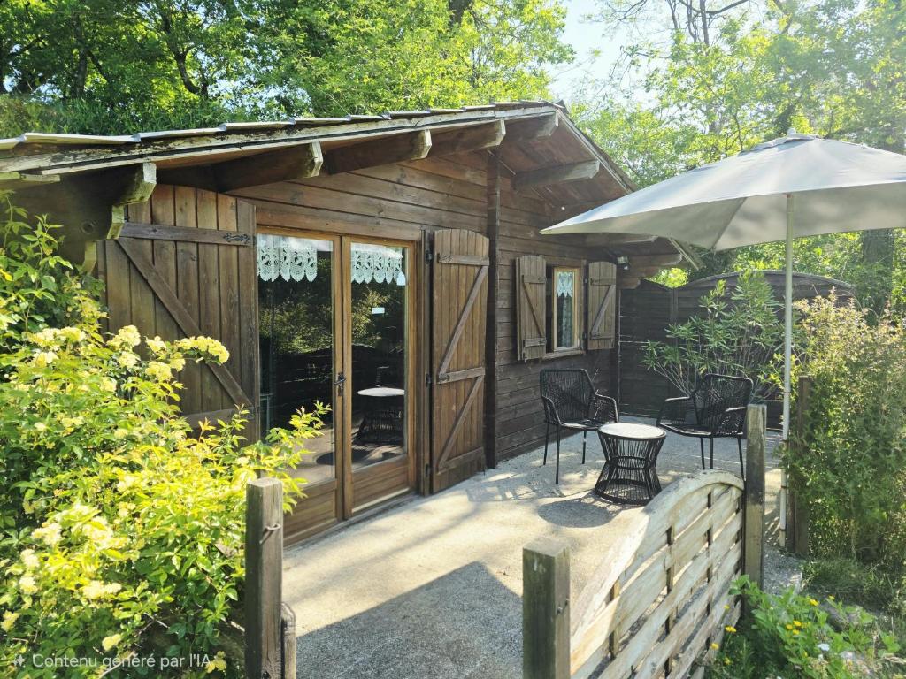 a small cabin with a table and an umbrella at Chalet Ty Kerouannec in Guilligomarcʼh