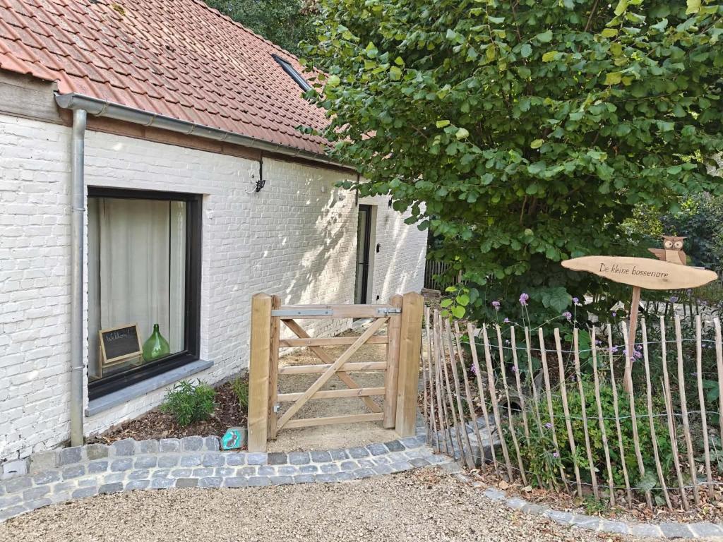 a fence with a wooden gate in front of a house at De kleine Bossenare in Maarkedal