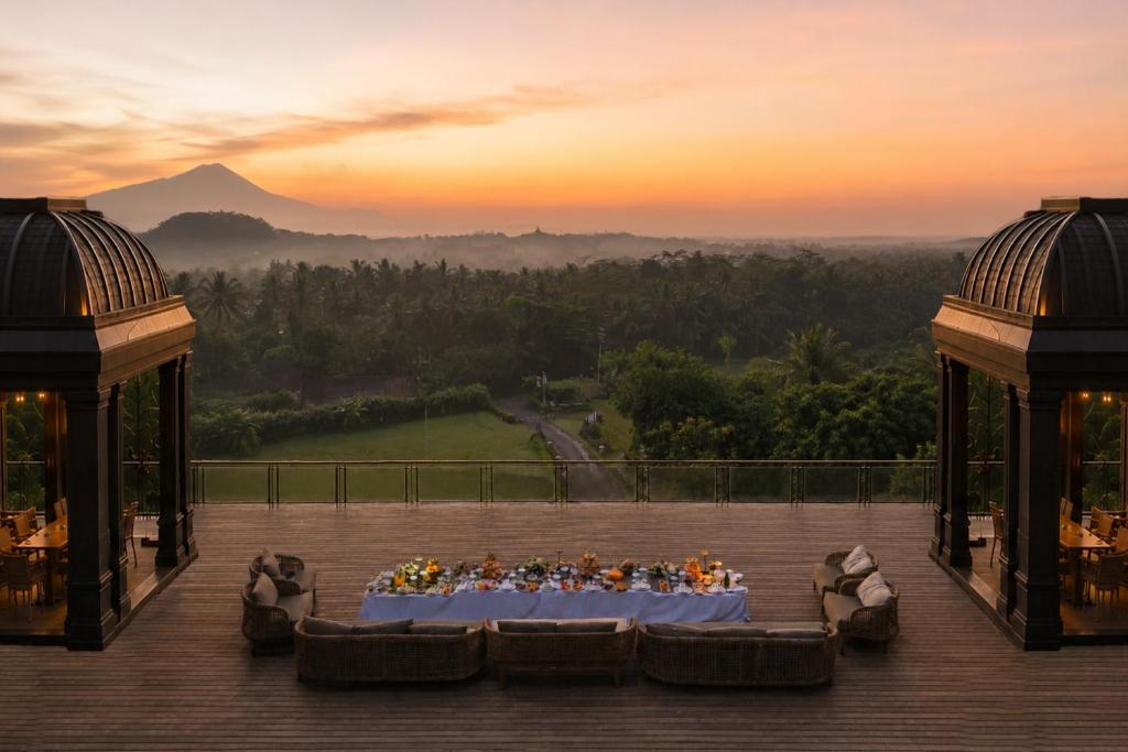 a group of people sitting at a table on a deck at Plataran Borobudur in Borobudur