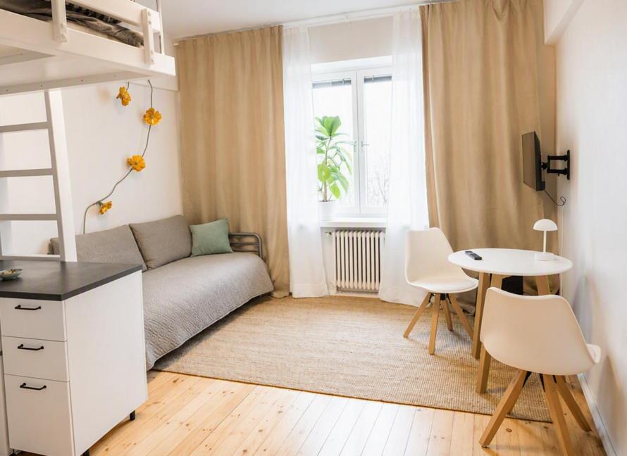 a small bedroom with a bed and a table and chairs at Alppila Lodge Studio in Helsinki