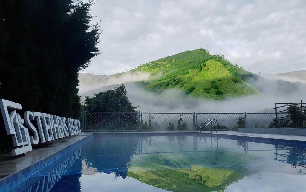 a swimming pool with a mountain in the background at Stephen's Legacy in Vattavada