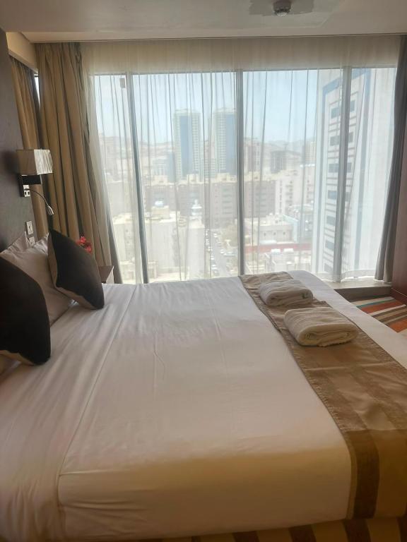 a large bed in a hotel room with a large window at فندق بياب العزيزية - Beyab Azizia Hotel in Mecca