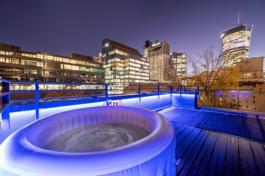 a hot tub on a deck with a city skyline at Unique Tower Business View Apartment in Warsaw