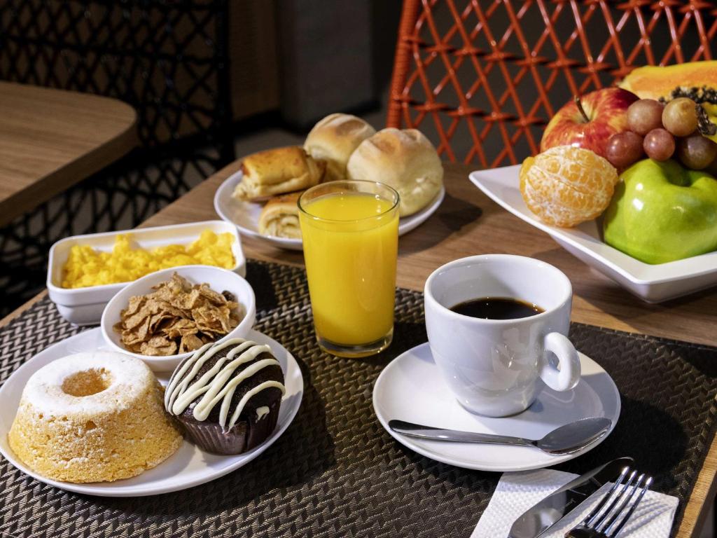 a table with plates of breakfast foods and a cup of coffee at ibis Ponta Grossa in Ponta Grossa