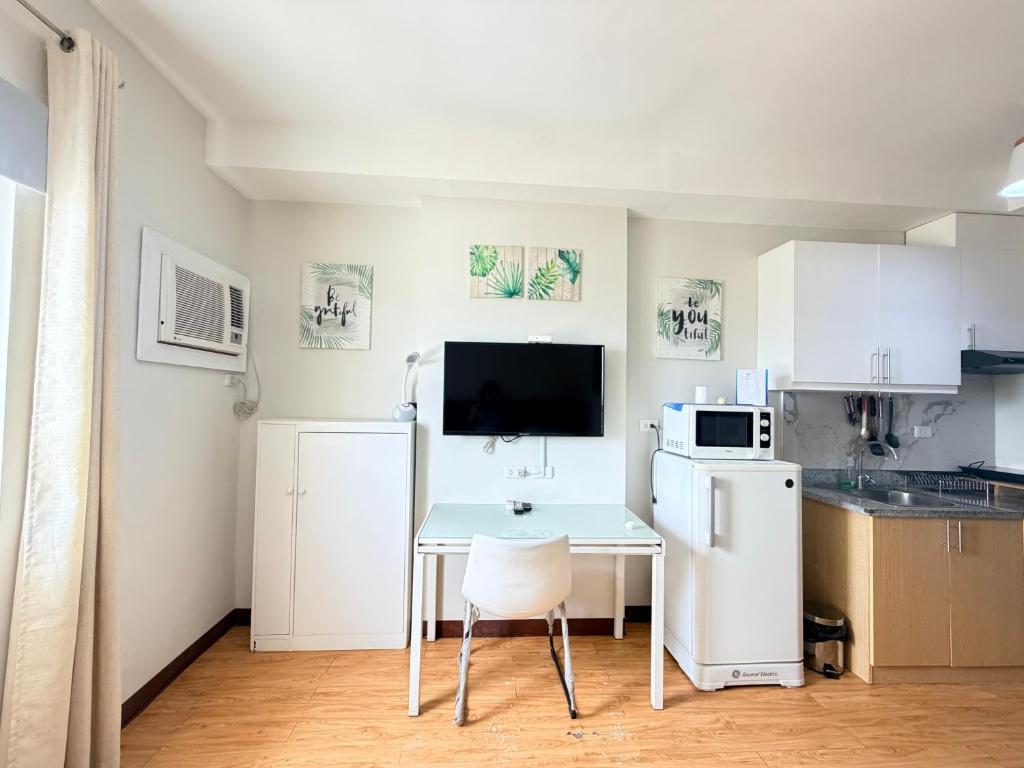 a small kitchen with a table and a white refrigerator at Compact Studio Unit l Mesaverte Residences 8th Floor in Pontud