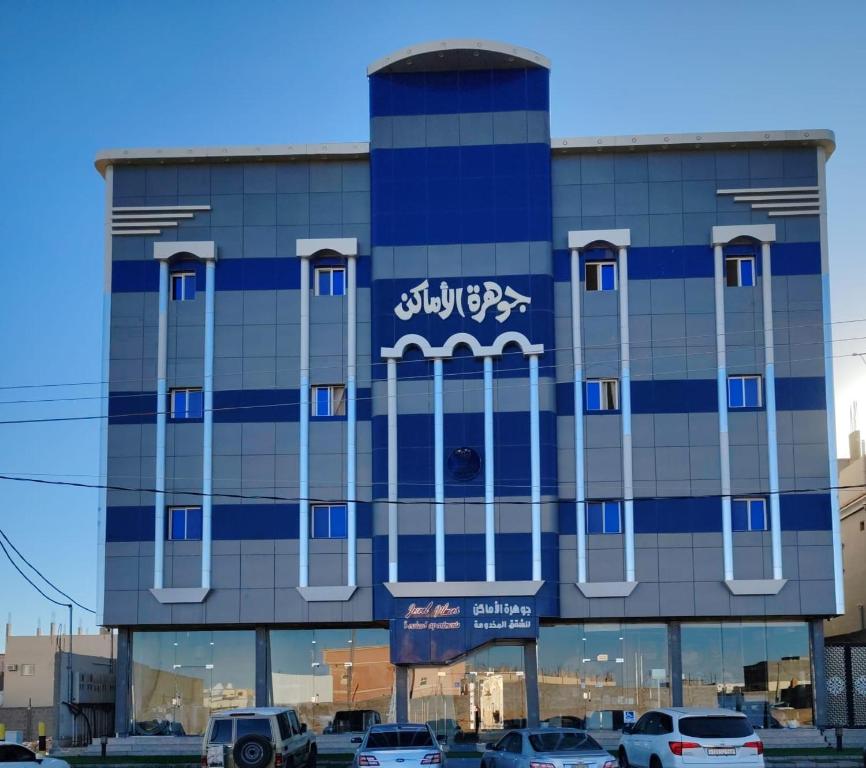 a building with cars parked in a parking lot at شقق جوهرة الأماكن للشقق المخدومة - أقتصادي in Taymāʼ