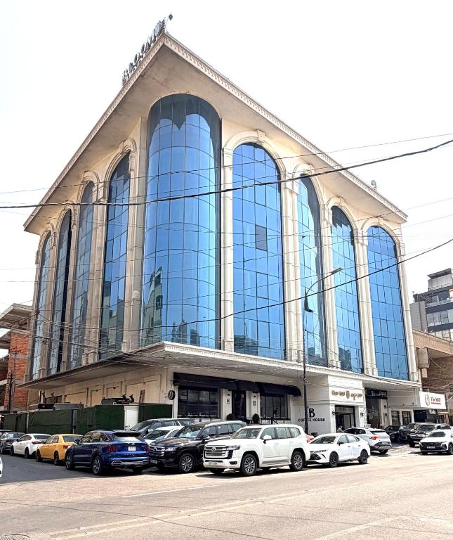 a large building with cars parked in front of it at Bloom Hotel in Baghdād