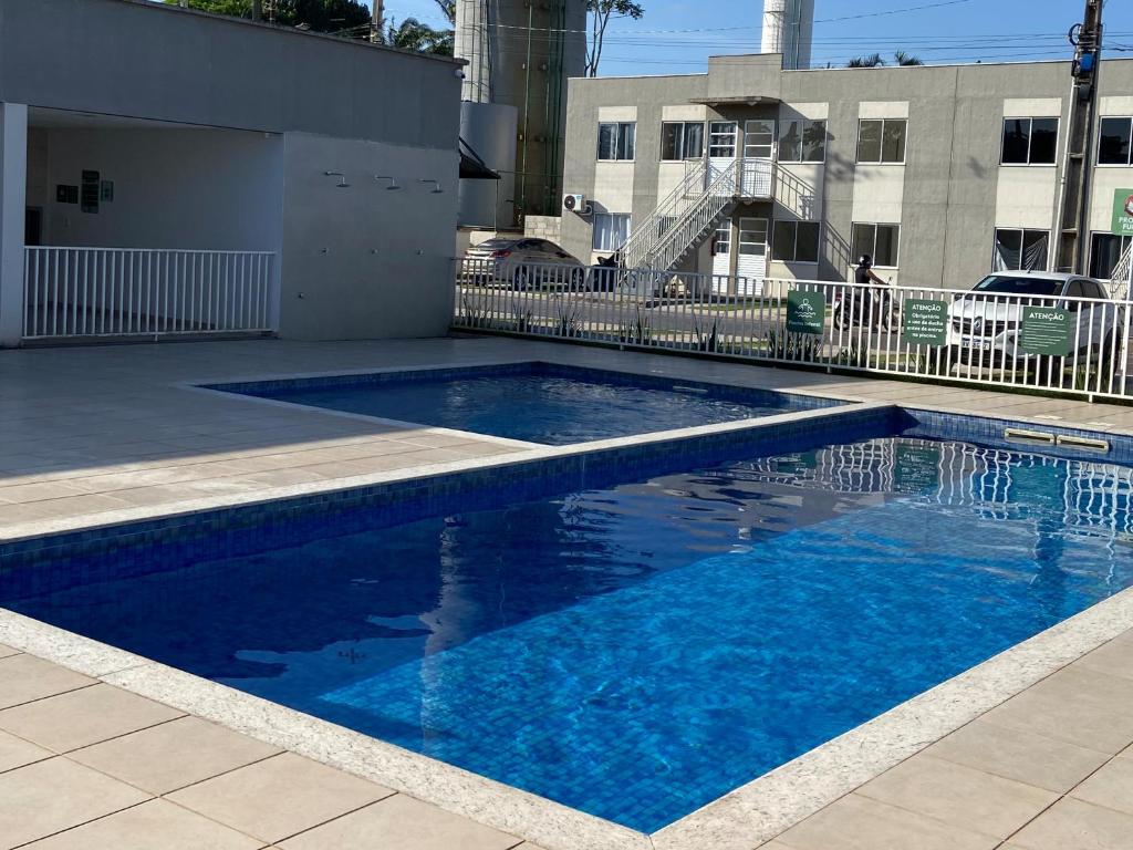 a swimming pool with blue water in front of a building at Townhouse Flat Térreo in Ananindeua