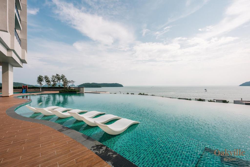 a swimming pool with lounge chairs next to the water at Assana Cenang Beachview oakville by sync in Pantai Cenang