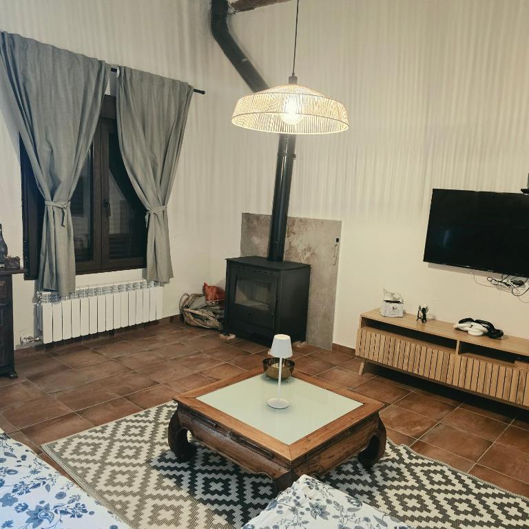 a living room with a table and a stove at Casa Rural El Jaral in Orihuela del Tremedal