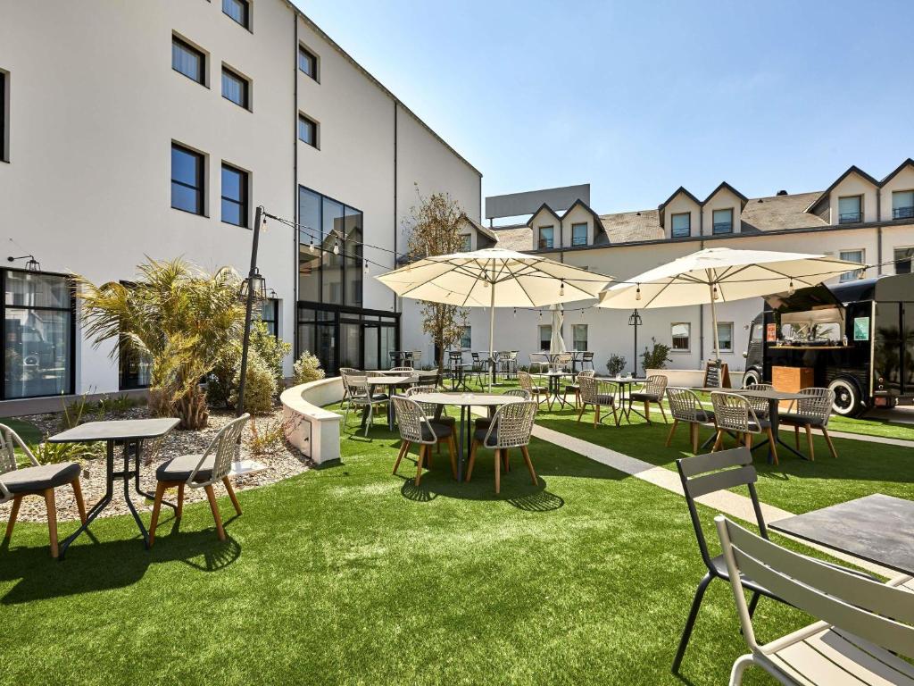an outdoor patio with tables and chairs and umbrellas at ibis Styles La Roche-sur-Yon in Mouilleron-le-Captif