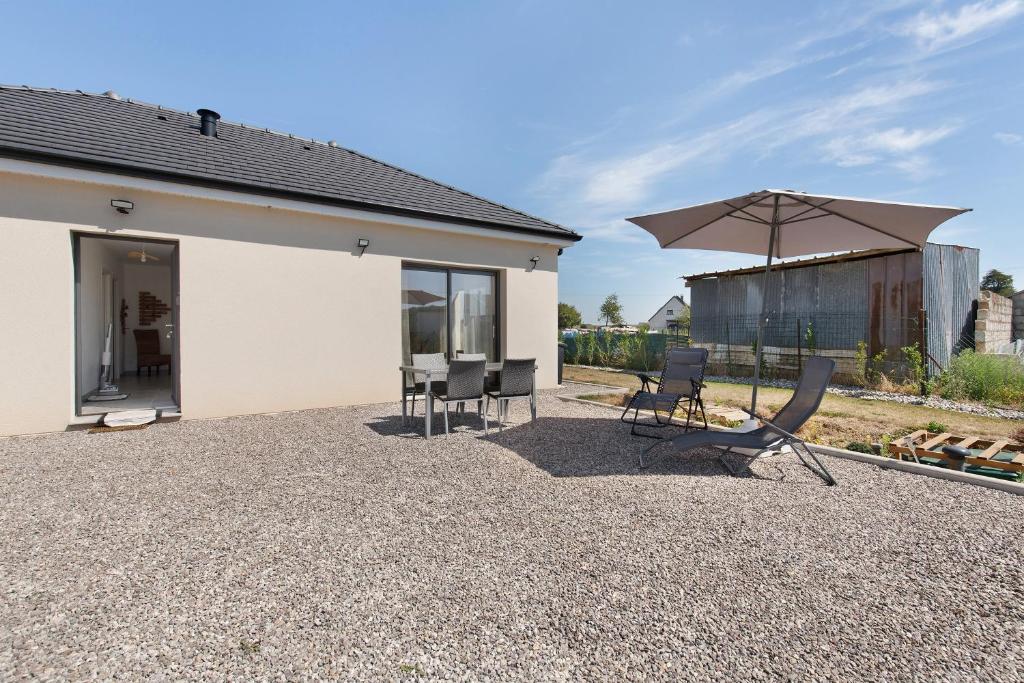 a patio with two chairs and an umbrella at Maison entre foret et mer in Millebosc