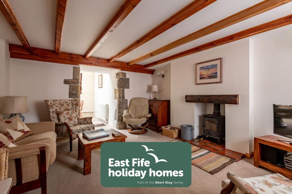 a living room with a couch and a fireplace at Mariners Cottage - Elie in Elie