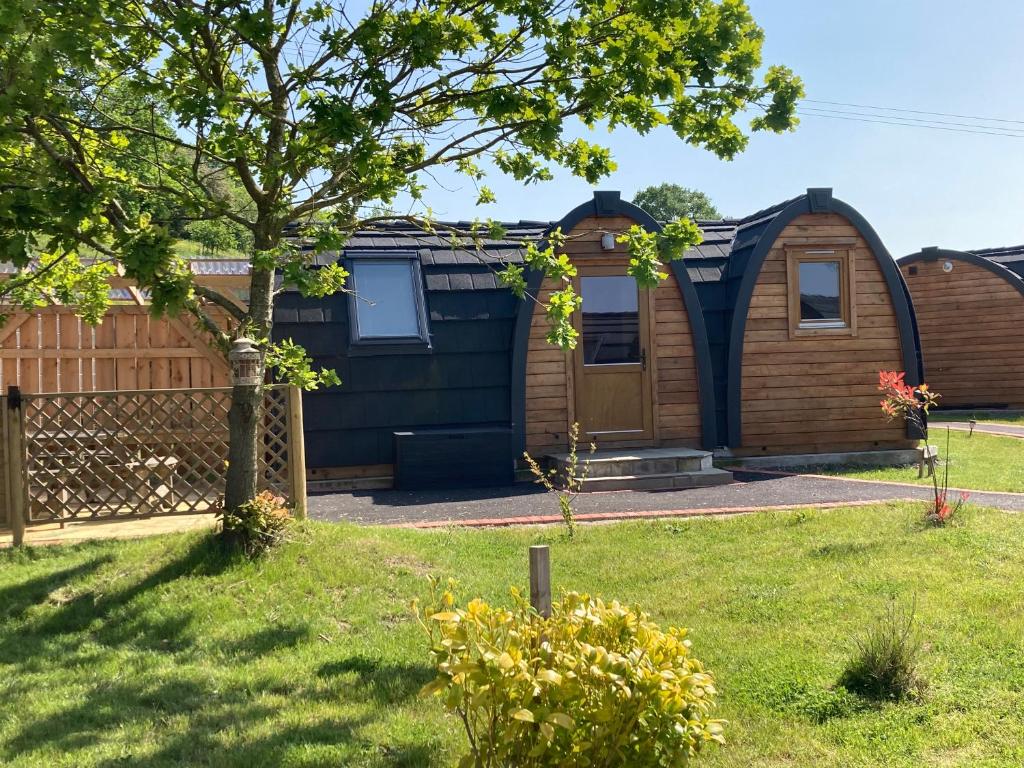 a house with a tree in a yard at Squirrel Glamping Pod in Leighton
