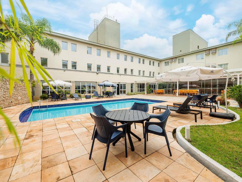 a hotel with a pool and tables and chairs at Ibis Styles Campinas Alphaville in Campinas