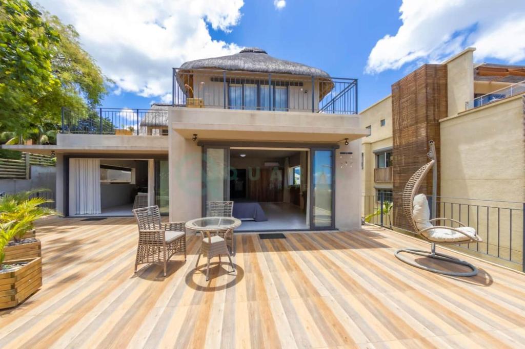 a home with a deck with chairs and a table at Beachfront villa by M&H in Tamarin