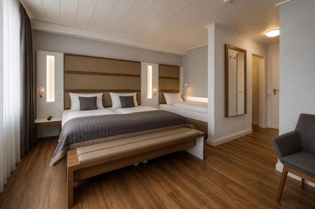 a large bedroom with two beds and a chair at Hotel Dortmund City in Dortmund