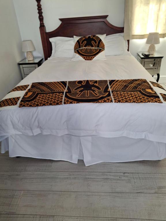 a bed with a brown and white comforter at Martha's Guesthouse in Gqeberha