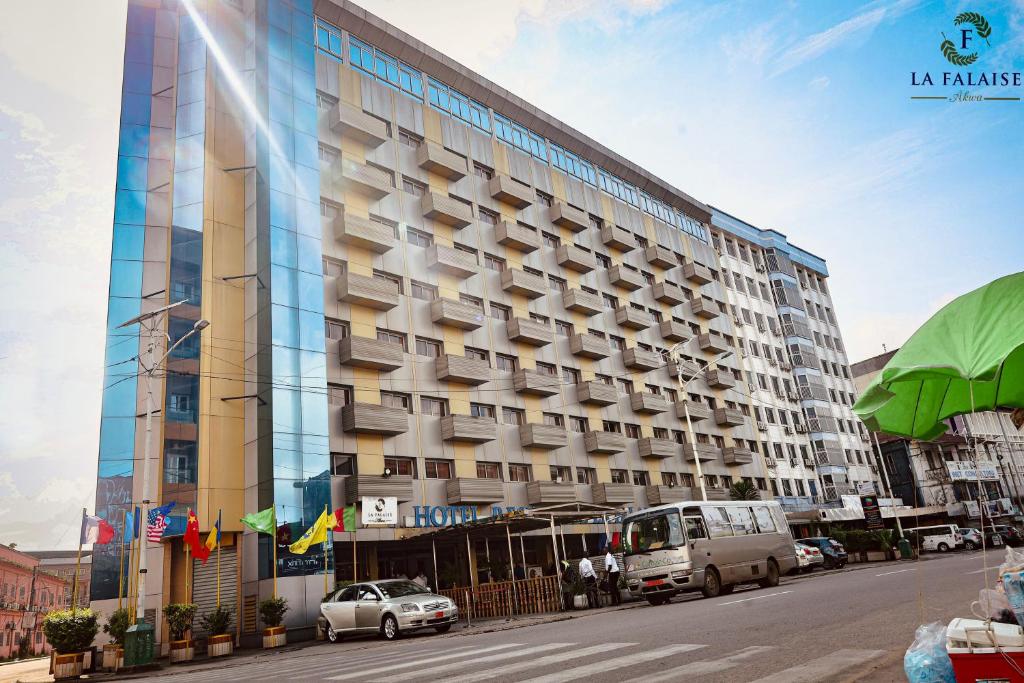 a large building with cars parked in front of it at Hotel Résidence La Falaise in Douala