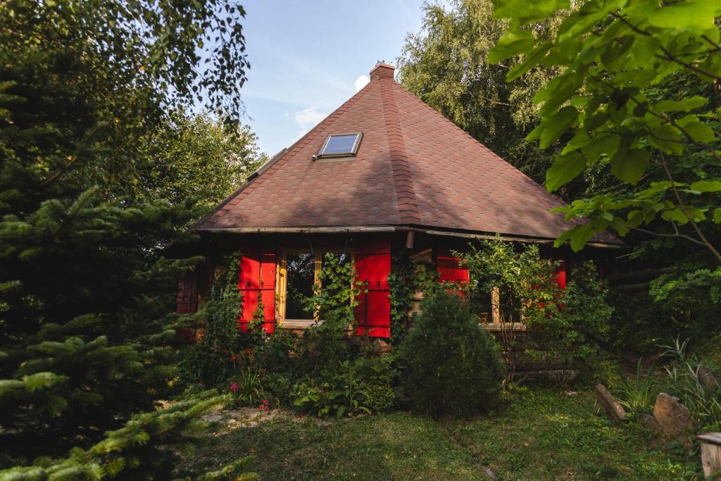 a small house with red windows and a roof at Bukowica Miła - Dom z sauną w sercu Natury 2000 in Wola Piotrowa