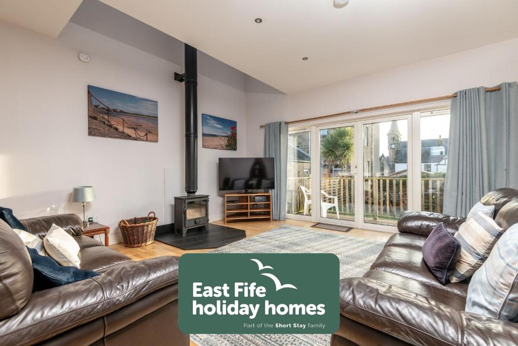 a living room with a leather couch and a television at Craiglea - Elie & Earlsferry in Earlsferry